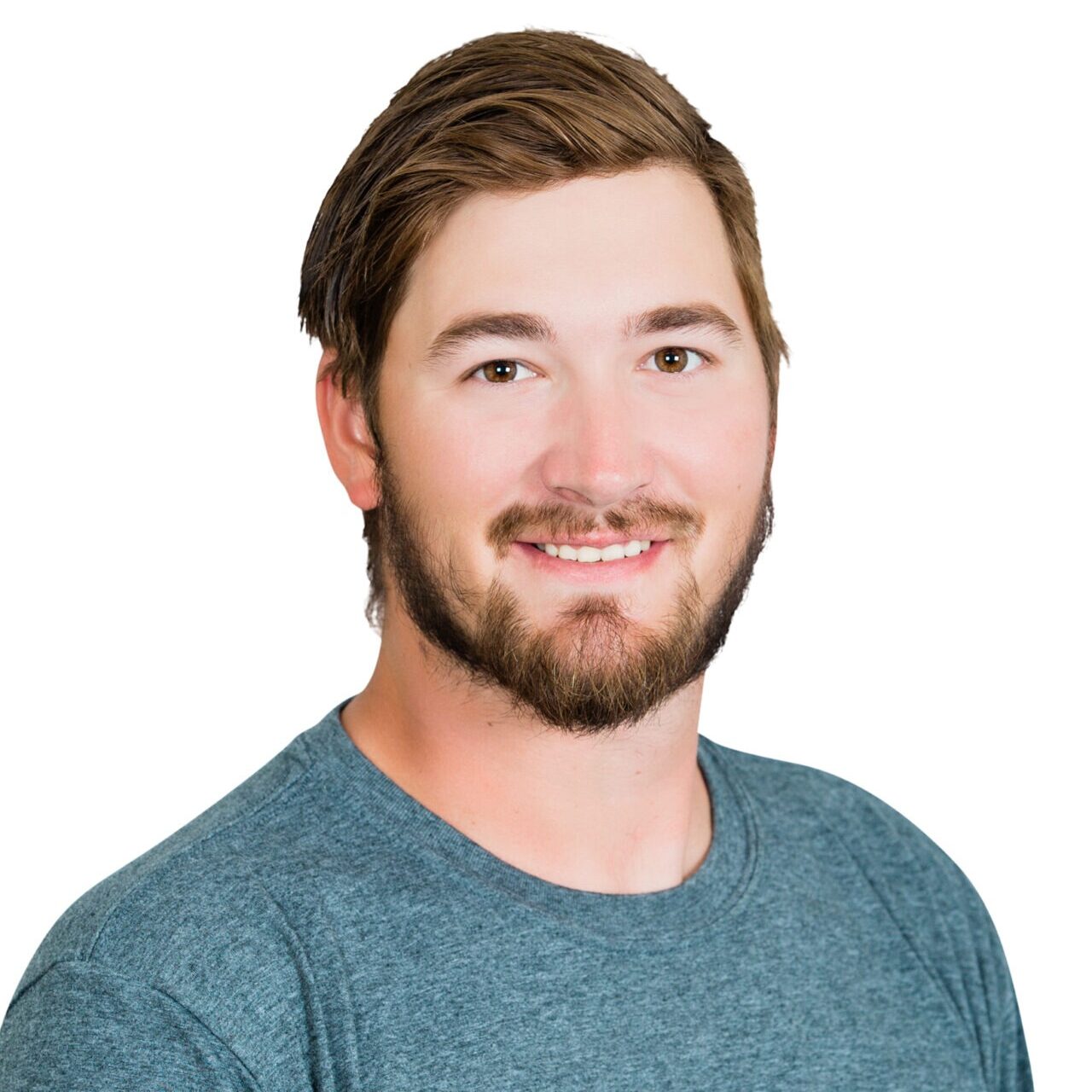 A person with short hair and a beard, wearing a blue shirt labeled "Whispering Pines Landscaping," smiles against a plain white background.