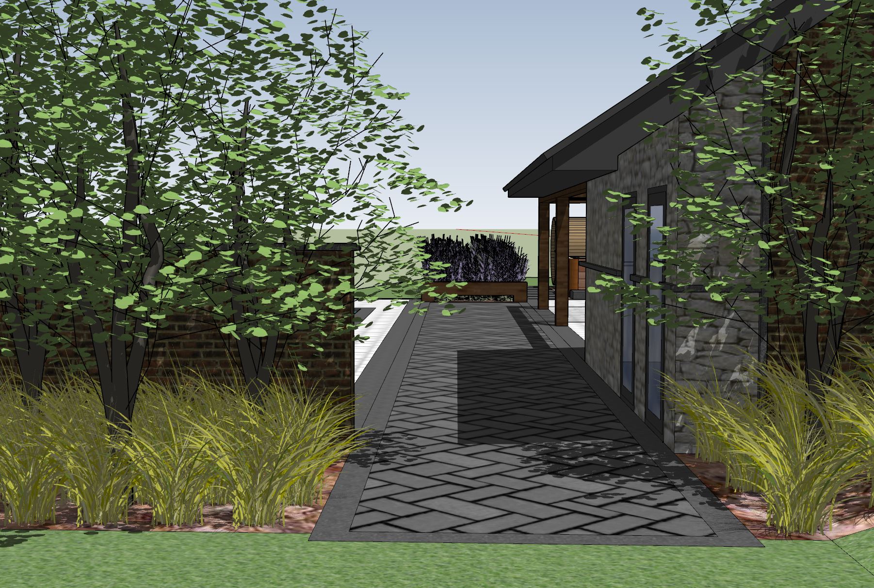 A stone pathway leads between lush trees and a modern building, featuring grass and a wood-finished bench at the end.