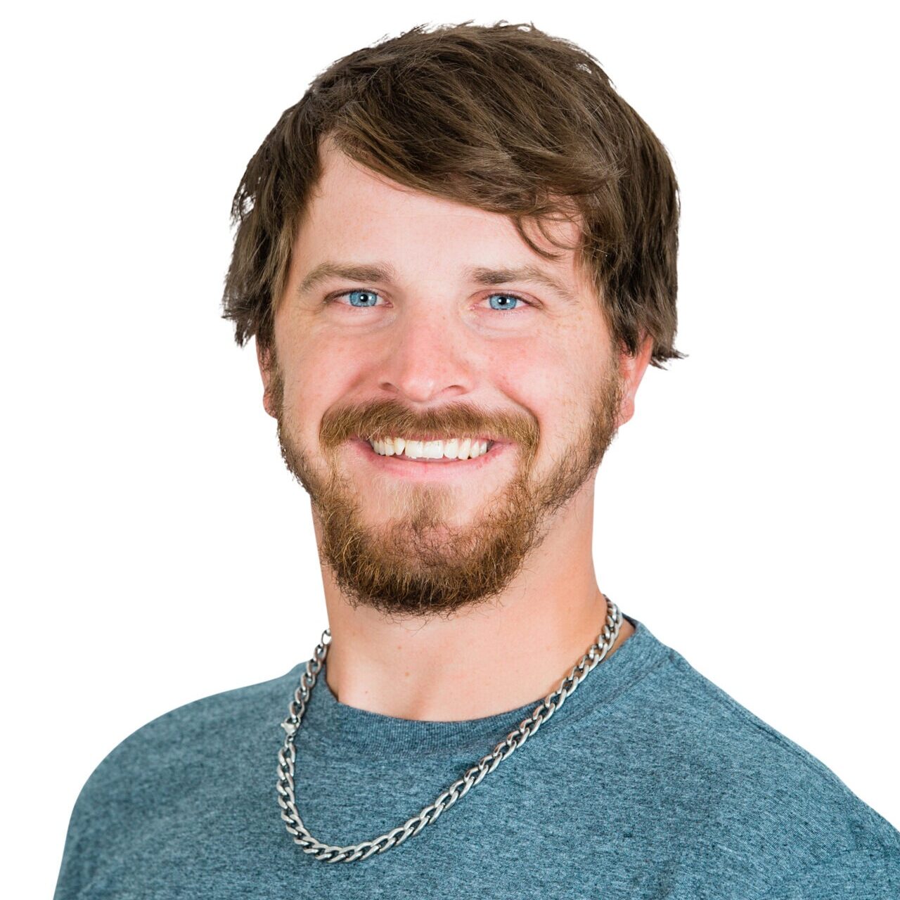 A smiling person with a beard, wearing a chain necklace and a t-shirt that says "Whispering Pines Landscaping." White background.
