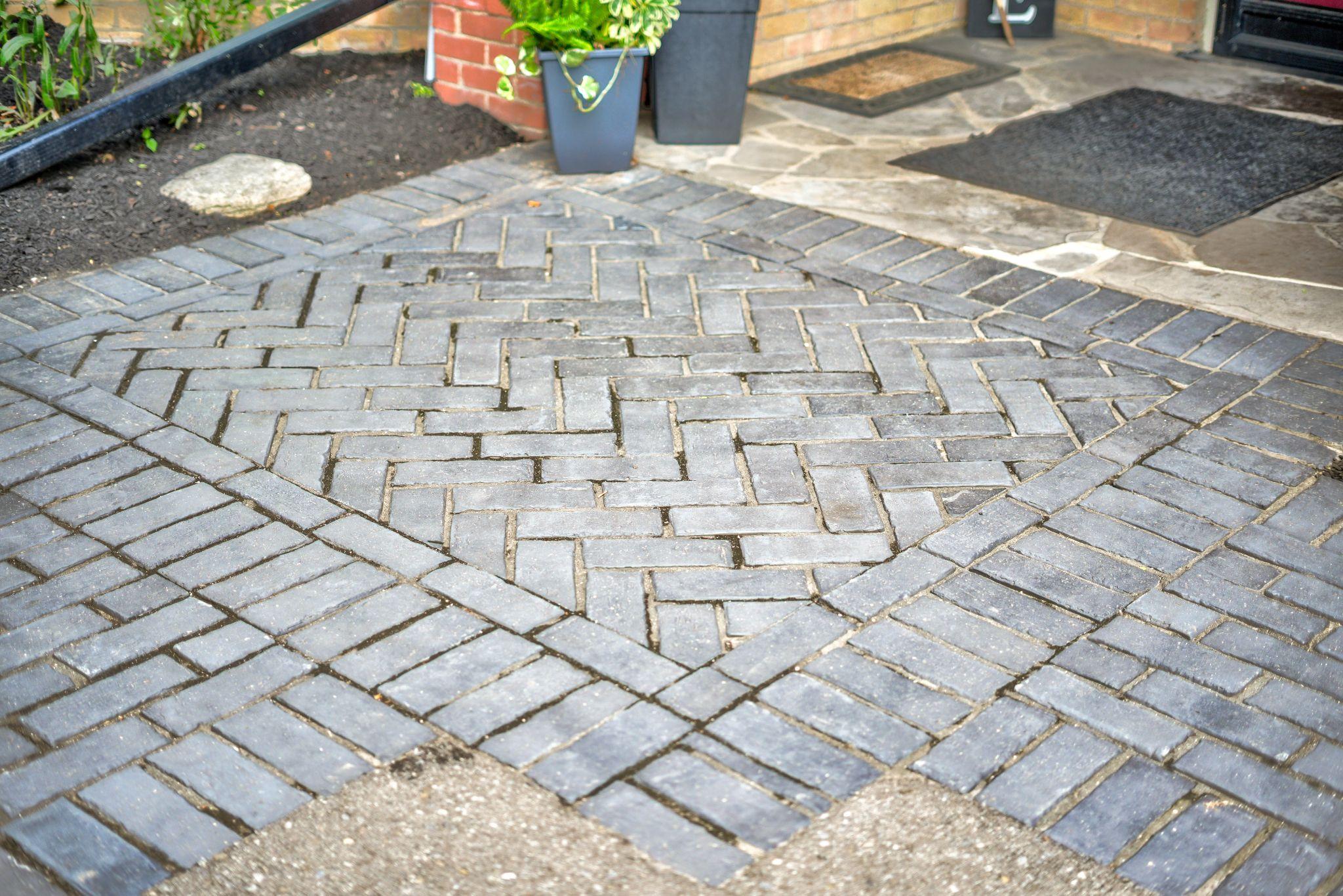 Herringbone-pattern interlock stone walkway leading to a home entrance.