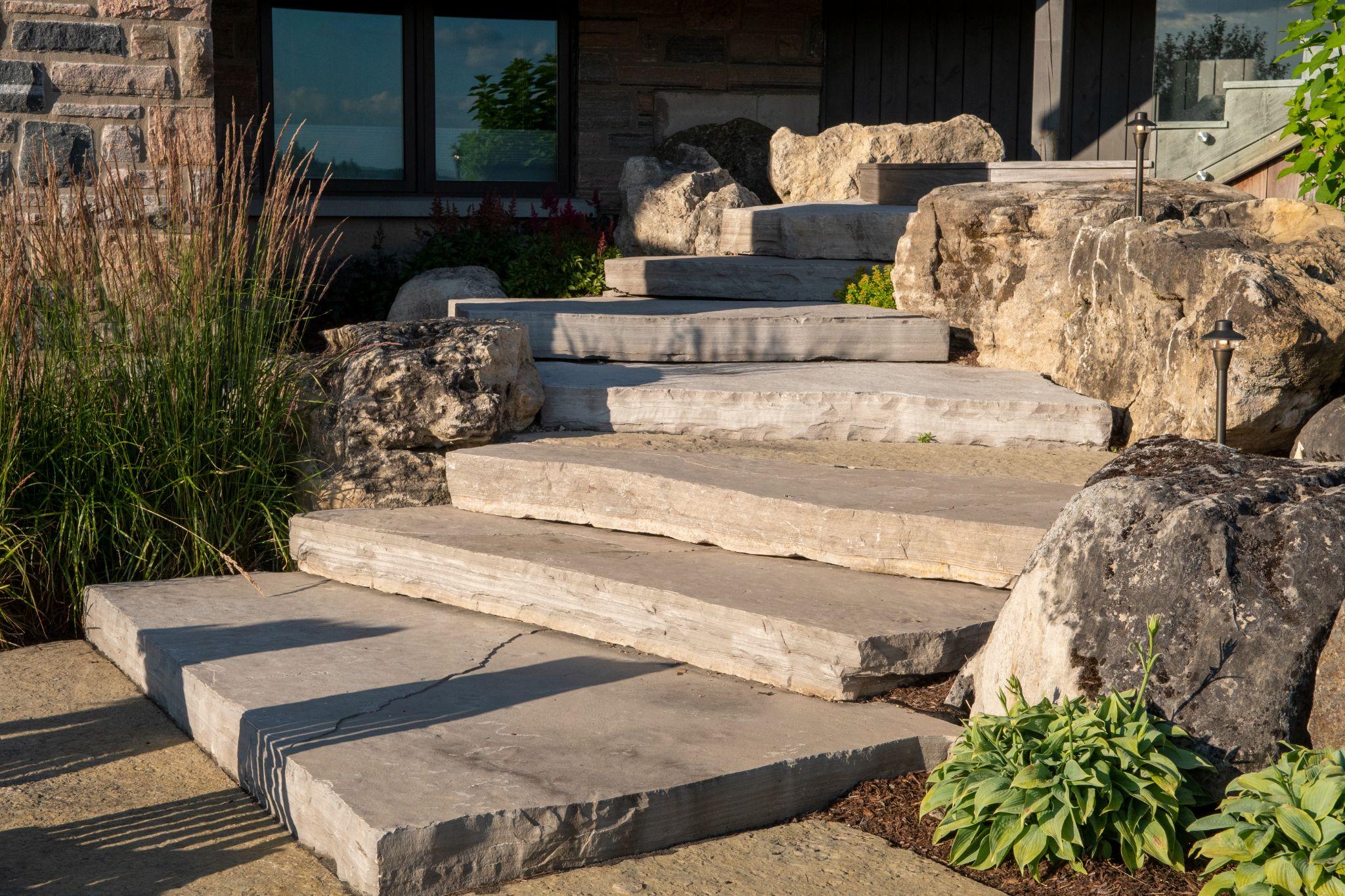 Natural stone steps with large boulders leading to a modern home entrance.