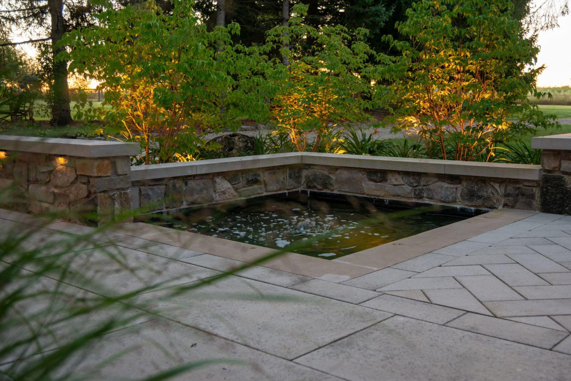 Reflecting pool at dusk, with natural stone seating wall and interlocking stone surround